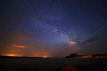 The Milky Way accompanied by clouds lit by Snake Creek campground lights and the city of Platte to the east.