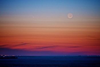 The waxing moon and comet Pan-STARRS (to the left of the moon) hang in the South Dakota sky.