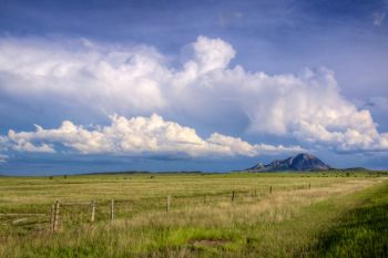 Bear Butte with distant storm clouds taken from Highway 79.