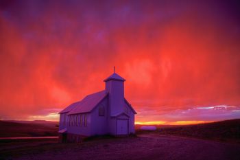 Rain colored by the setting sun above Our Lady of the Prairie Church in rural Harding County.