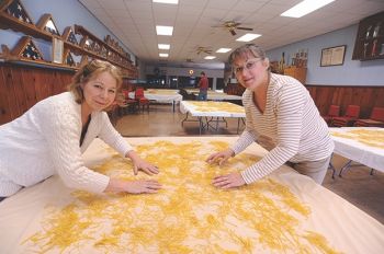 Susan Schroeder and Barb Perk turn drying noodles in Tabor's Legion Hall.