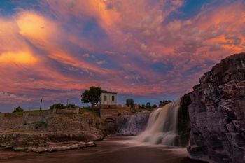 Sunset light coloring dissipating rain clouds over Falls Park in Sioux Falls.