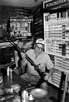 Curt Carter cleans a shotgun in his small workroom. He and his son inspect every gun that they accept in trade.