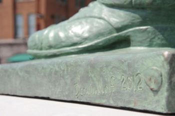 The artist’s signature is scratched below Pettigrew’s left shoe.