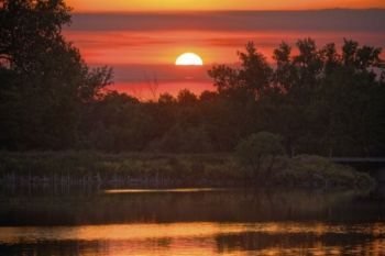 Sunset over the earthen dam and spillway of Lake Hiddenwood State Park.