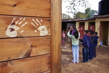 A wooden, portable classroom is decorated by child handprints at The Learning Center.