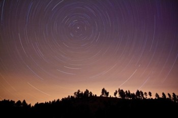 The stars above a forested ridge in Custer State Park. Low clouds illuminated by the lights of Rapid City entered the scene at the end of the exposure to give the unique color above the ridge.