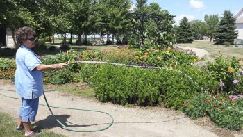 Marjean Waltner waters the flowers at Freeman’s arboretum.