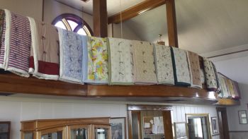 Immanuel Lutheran Church parishioners sell the quilts that line the church’s balcony.