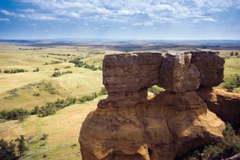 A large column of weathered sandstone frames a view across the plains to the 
east of the Cave Hills where Custer’s Expedition passed about three-quarters of a mile away on July 12, 1874. The Slim Buttes are visible 20 miles off on the distant horizon.