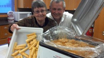 Patti Frazee (one of the kitchen helpers) with krumkake and Al Mathiasen with a roaster of klub. Photo from Kathy Mathiasen.