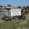 Threshing machines and other farm equipment make sturdy billboards, like this one pointing travelers to the Jamesville Hutterite Colony near Utica. Photo by Chris Moore.