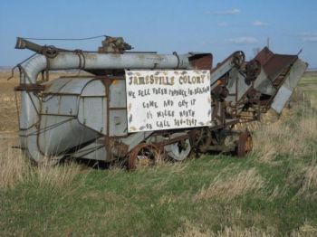 Threshing machines and other farm equipment make sturdy billboards, like this one pointing travelers to the Jamesville Hutterite Colony near Utica. Photo by Chris Moore.