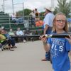 Ten-year-old Chloe Holzwarth displays the Sam Bat for the crowd while auctioneer Lanning Edwards takes bids between games of the state amateur baseball tournament in Mitchell Saturday. Photo by Craig Wenzel/Wessington Springs True Dakotan