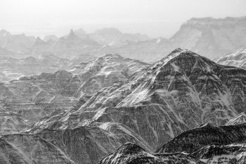 Sunlight breaking through a winter flurry at Badlands National Park in black and white.