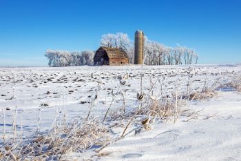A red barn and silo under a clean blue winter sky in rural Moody County.