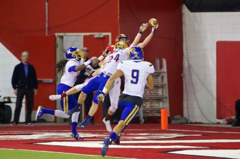 Players from both teams reach for a pass to the end zone in 2015.