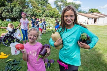 Harvest day with a tomato, eggplants, a butternut squash and two happy kids.