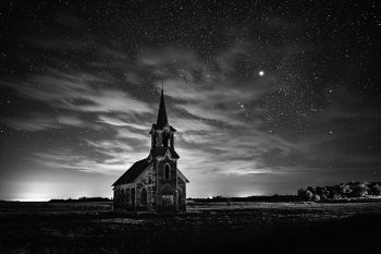 Stars with clouds and faint aurora in rural Roberts County in black and white.