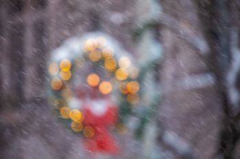 Snowfall in front of holiday wreath.