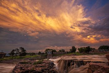 Sunset coloring retreating storm clouds over Falls Park in Sioux Falls.