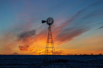 A prairie windmill at sunset.