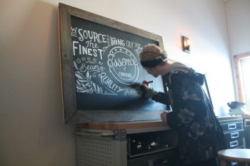 Christie Harris works on a chalk mural for Essence of Coffee.