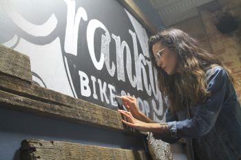 Laurel Antonmarchi at work on a sign inside Cranky's Bike Shop.