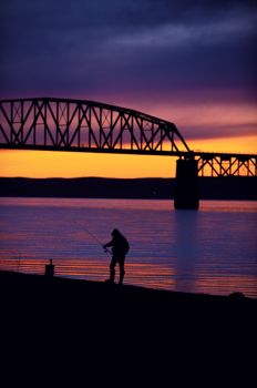 A fisherman works the shoreline between the railroad and interstate bridges at Chamberlain.