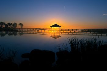 A gazebo and boardwalk frame the Sully County sunrise as it glows atop a lake on Paul and Cheryl Nelson's farm.